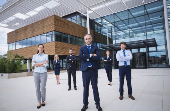 Group of confident businesspeople standing with arms crossed outside office building